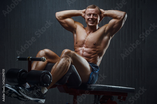 Fitness man pumping up abs muscles in gym
