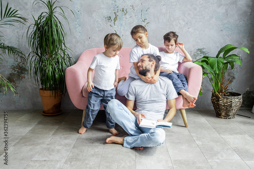 Cute young father is reading a book to his children. Happy family togetherness and fatherhood. Children spend time with their father. photo