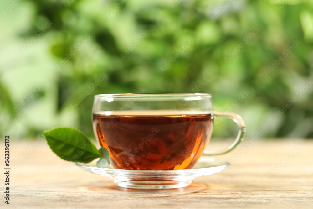 Cup of black tea on wooden table against blurred background. Space for text Cup of black tea on wooden table against blurred background. Space for text