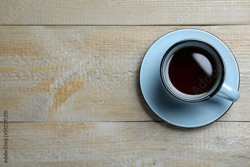 Cup of aromatic black tea on wooden table, top view. Space for text