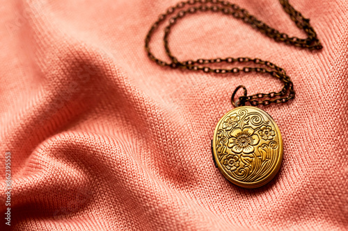 old bronze antique locket on a soft pink fabric background, vintage jewelry