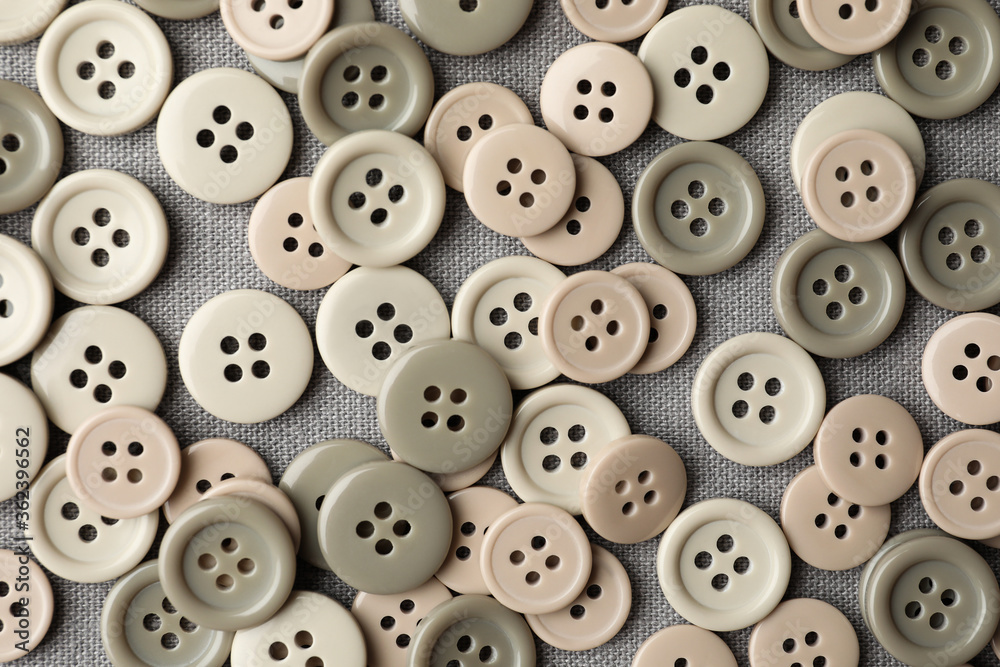 Many plastic sewing buttons on grey fabric, flat lay Many plastic sewing buttons on grey fabric, flat lay