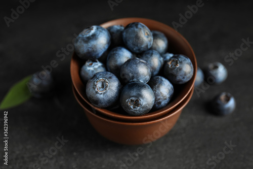 Fresh ripe blueberries in bowl on dark table  closeup