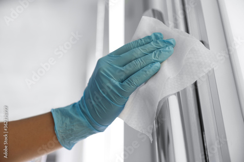 Woman cleaning door handle with wet wipe indoors, closeup photo