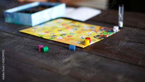 Board game board, chips, cube, timer on a dark wooden table and hands in the background. The concept of teamwork, intellectual relaxation, corporate event, playing at home with children. Copy space