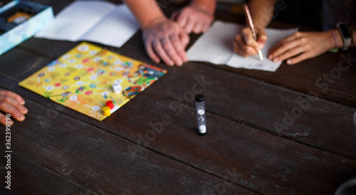 Board game board, chips, cube, timer on a dark wooden table and hands in the background. The concept of teamwork, intellectual relaxation, corporate event, playing at home with children. Copy space