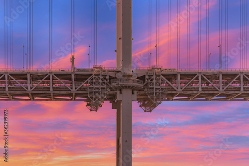 Close-up on the pillar of the Rainbow Bridge suspended in a double layer with the shuto expressway Daiba route on the upper floor and the automated yurikamome monorail line below against a sunset sky. photo