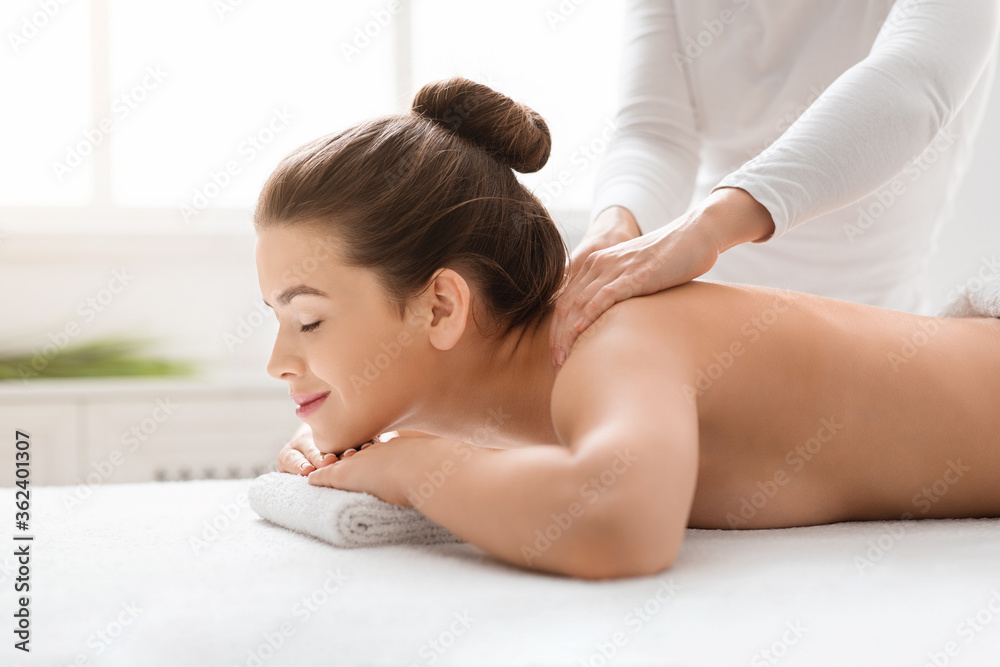 Masseuse rubbing young woman shoulders at spa Masseuse rubbing young woman shoulders at spa