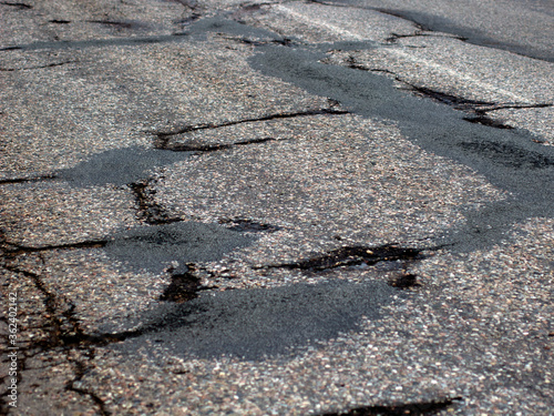 Damaged Broken city asphalt road with a lot of pits. Depressive urban landscape. bad road.