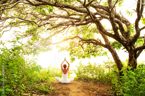 Woman practicing yoga at sunset