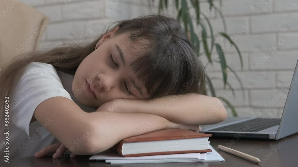 Tired of books. The young girl fell asleep on the books next to the laptop. Tired of books. The young girl fell asleep on the books next to the laptop.