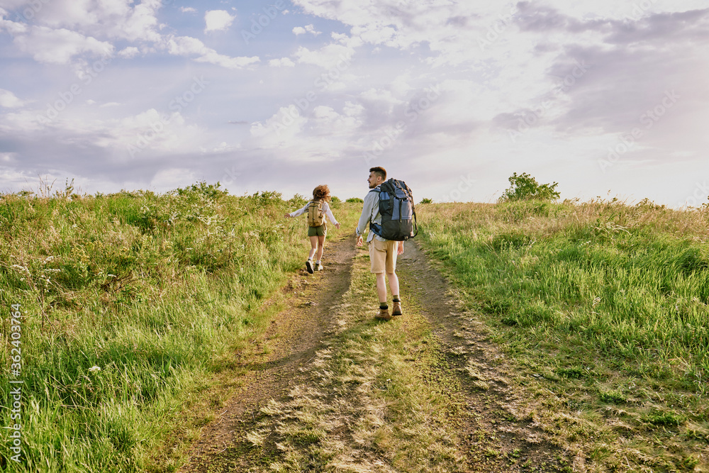 Rear view of young female hiker with backpack running down country road