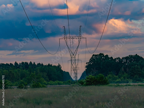 Słupy linii elektrycznej na tle wieczornego, zachmurzonego nieba. photo