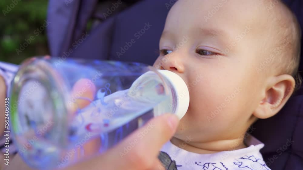 Portrait One Year Old Baby Drinks Water In Park At Picnic Portrait One Year Old Baby Drinks Water In Park At Picnic