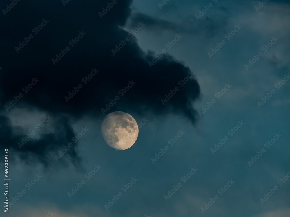 Ciemna chmura na tle wschodzącego księżyca.