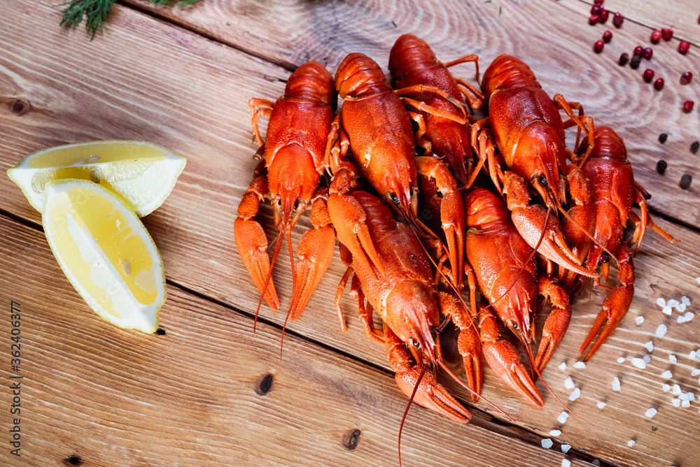 Boiled crayfish on a wooden table among spices, lemon and dill. The concept of food, beer snacks, relaxation in a bar and restaurant Boiled crayfish on a wooden table among spices, lemon and dill. The concept of food, beer snacks, relaxation in a bar and restaurant