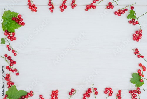 Frame of red currant berries on a wooden background with copy space. For summer lettering.