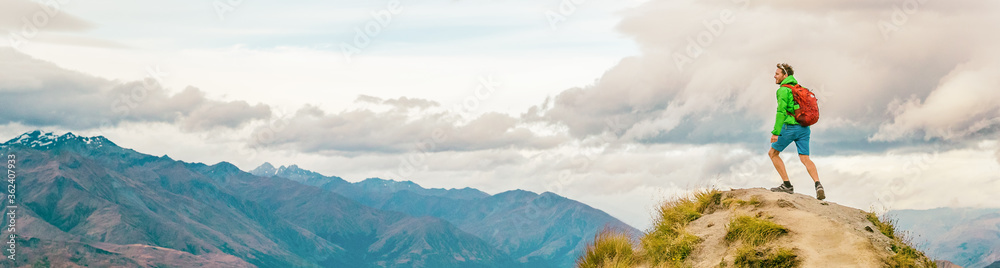 Hiking man wanderlust adventure and travel concept explorer with hiker looking at view. Hiker tramping up famous hike to Roys Peak on South Island, New Zealand. Panoramic Bannner.