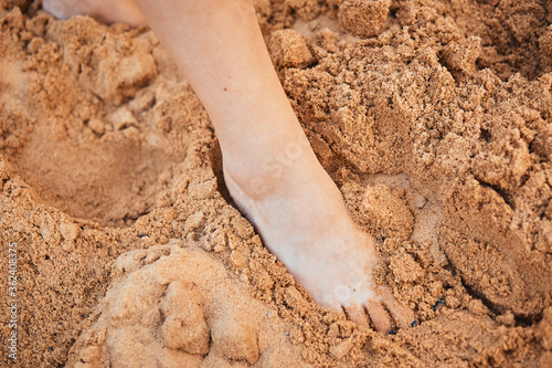Close-up of the legs and feet of a girl walking on the wet sand of the beach