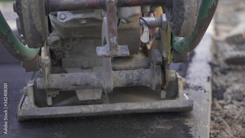 Vibratory asphalt paving machine on the sidewalk filmed close-up.Road works pavement repair hard work.Video clip