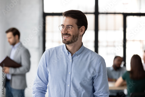 Head shot confident happy company boss entrepreneur standing in work space look away. Career growth, sales increase, prosperous business owner, promoted employee vision about successful future concept
