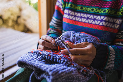 Woman knits a hat from woolen yarn.