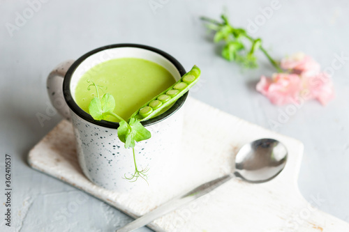 Homemade fresh green pea cream soup with pea sprouts and flowers