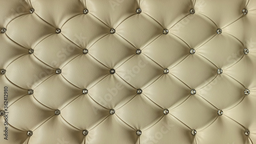 Stylish beige soft leather upholstery of sofa. The material is decorated with buttons in the form of crystals. Upholstery leather pattern background.