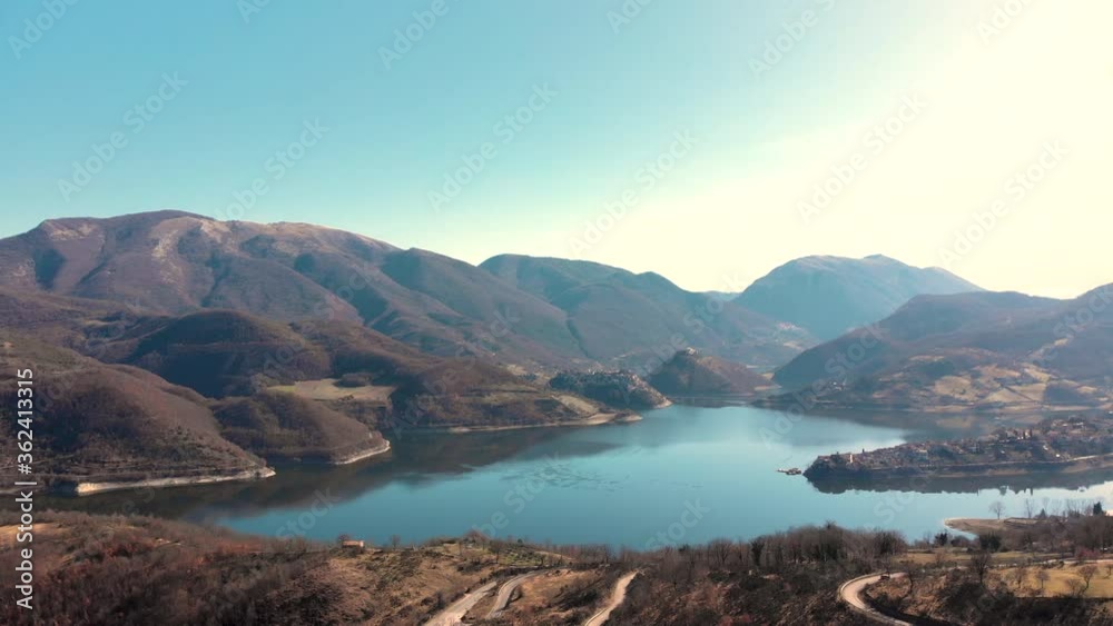 Serene Lake By The Mountains Under The Clear Blue Sky During Summer In Italy. - aerial drone shot Serene Lake By The Mountains Under The Clear Blue Sky During Summer In Italy. - aerial drone shot