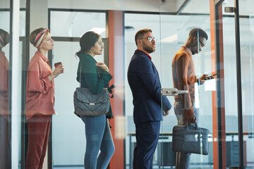 Side view at multi-ethnic group of business people standing in line in office behind glass wall, copy space