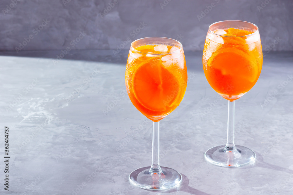 Aperol spritz cocktail on gray background. Two glasses of aperol spritz with orange slised. Summer cocktail in glass. Copy space