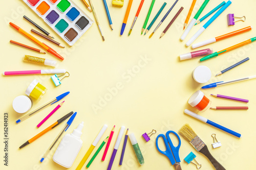 Colored different school supplies on yellow paper background. Flat lay, top view, copy space.