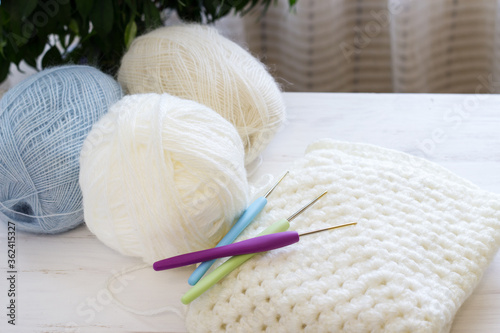 Cozy homely atmosphere. Balls for knitting in natural colors. Female hobby knitting. Blue, beige, white. Balls and hooks for the implementation of a knitted project. Copy space.