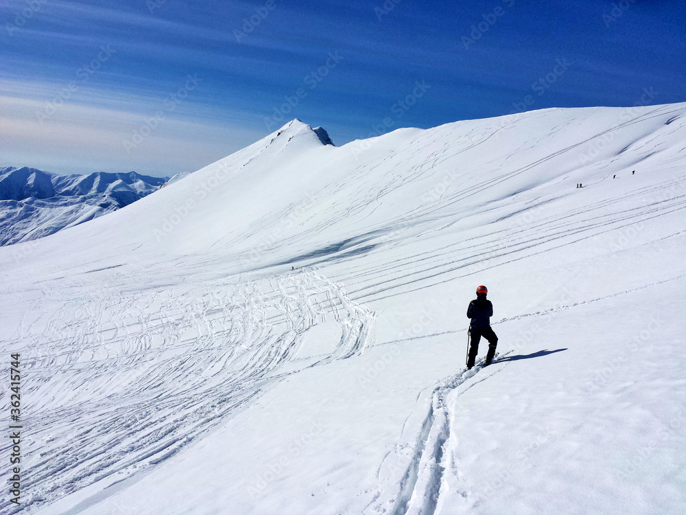 Skier on the top of mountain going through fresh snow 