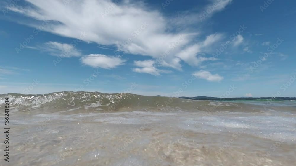 waves rolling ashore towards the camera against a blue sky, bright sunny day, close-up shot from a low angle, slow motion waves rolling ashore towards the camera against a blue sky, bright sunny day, close-up shot from a low angle, slow motion