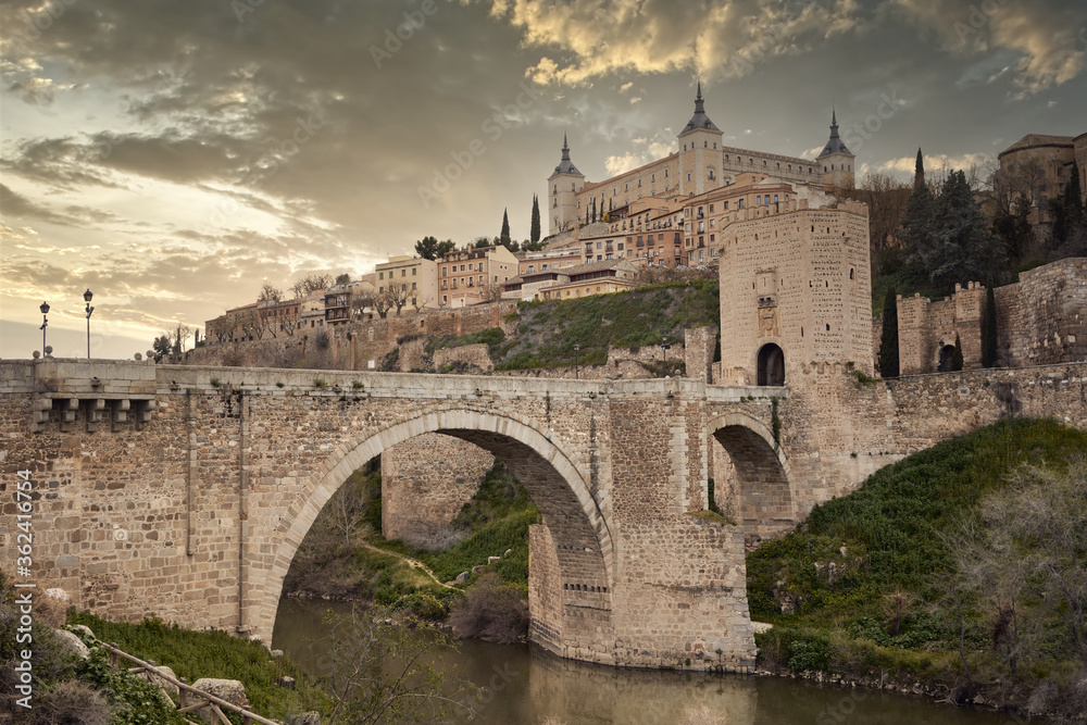 Toledo in Spain with Tagus River and Roman bridge Puente de Alcantara. Famous UNESCO World Heritage Site.