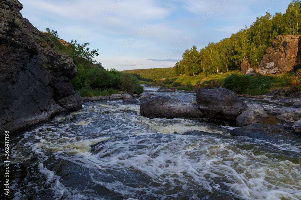 Ural Mountains. Rocks and rocky rifts on mountain river in summer. View on valley and the river Iset with rocky banks. Ural Mountains. Rocks and rocky rifts on mountain river in summer. View on valley and the river Iset with rocky banks.