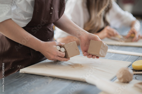 White clay preparation for work. Cutting layers of clay pieces for sculpting in the workshop of a potter Close-up. Raw bar of clay on the old wooden table in pottery. photo