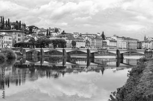 Florence or Firenze, Ponte delle Grazie bridge across the Arno river, reflections on the water, Tuscany, Italy. Monochrome image, black and white.