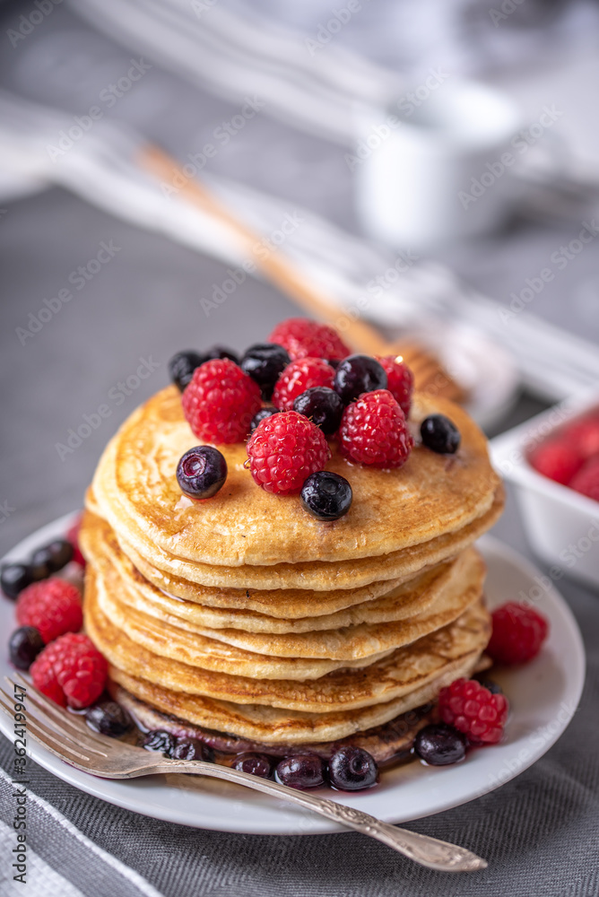 Homemade pancakes with raspberries and blueberries on grey napkin. Homemade pancakes with raspberries and blueberries on grey napkin.
