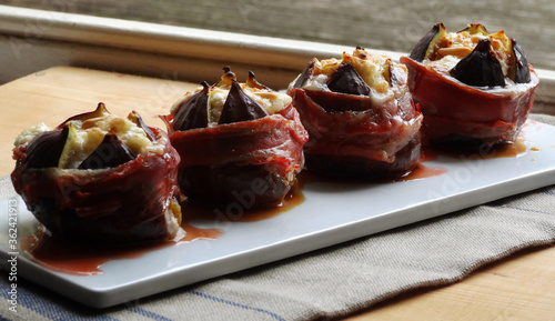 Baked prosciutto wrapped Turkish figs stuffed with goat cheese and pine nuts. photo