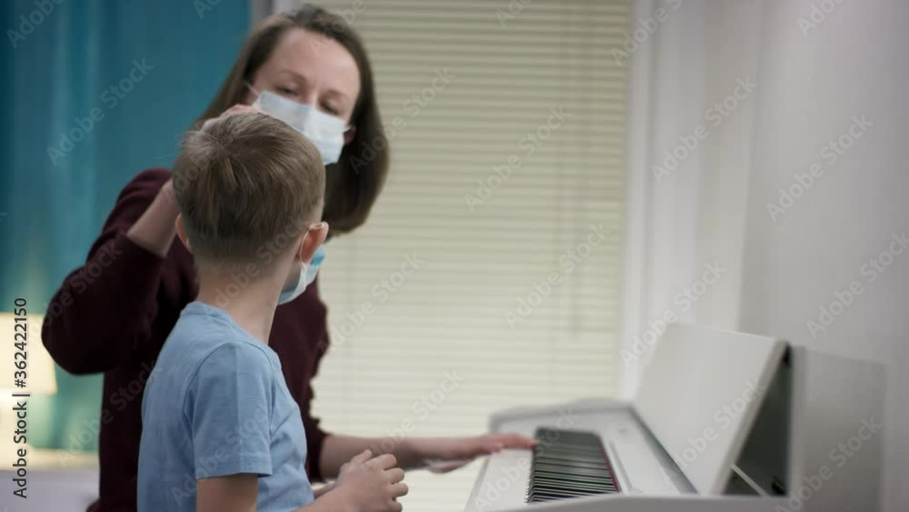 Closeup filming of a mom bracing up her boy to learn playing tunes on the piano by patting his head during Covid19 outbreak Closeup filming of a mom bracing up her boy to learn playing tunes on the piano by patting his head during Covid19 outbreak