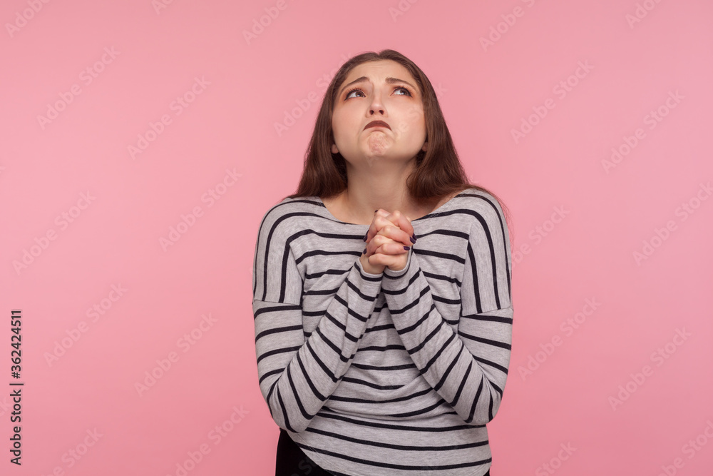 Please god, I'm begging! Portrait of unhappy woman looking up with beseeching imploring expression, praying and asking heartily, feeling desperate urging help. indoor studio shot, yellow background
