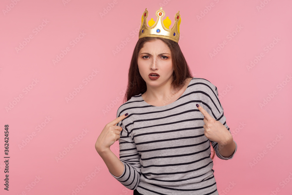 I'm boss! Portrait of selfish egoistic woman with golden crown on head pointing herself and looking with arrogance, declaring her authority, leadership. indoor studio shot isolated on pink background I'm boss! Portrait of selfish egoistic woman with golden crown on head pointing herself and looking with arrogance, declaring her authority, leadership. indoor studio shot isolated on pink background