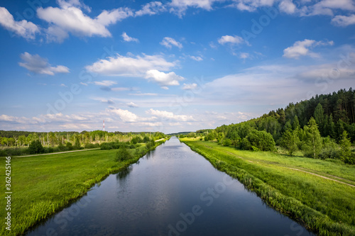 landscape of a beautiful wide river or channel on a sunny day with blue reflection with beautiful clouds in the water