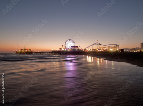 Dusk view of popular Santa Monica pier reflecting in pacific ocean water in Southern California. © trekandphoto