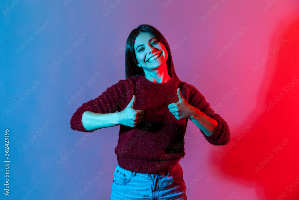 Well done, excellent job! Neon light portrait, joyful woman showing double thumbs up, gesturing like to camera and smiling broadly, expressing approval, positive feedback. indoor studio shot isolated