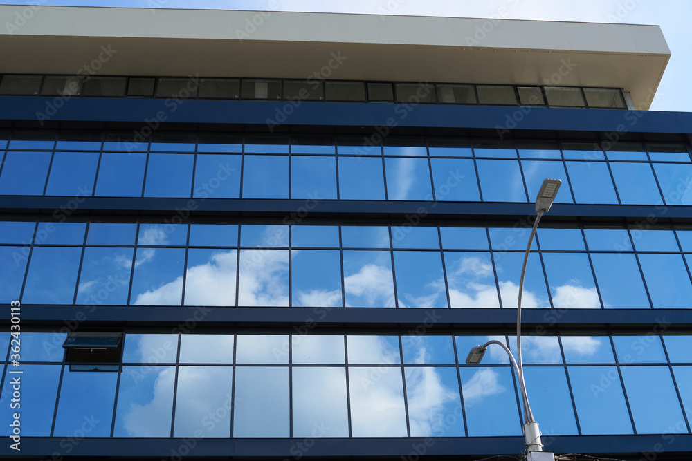 facade of a modern building on a bright Sunny day, blue sky and clouds reflecting in a glass, beautiful exterior of the new building facade of a modern building on a bright Sunny day, blue sky and clouds reflecting in a glass, beautiful exterior of the new building