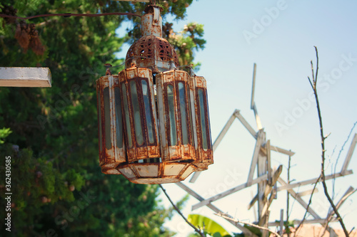 An old and rusty lantern suspended from a tree in the open air.