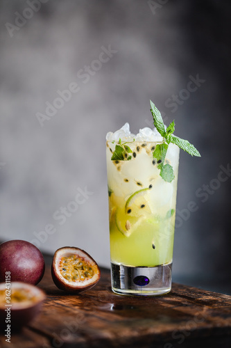 Passion fruit mojito cocktail och mocktail with lime, in a high glass on gray background